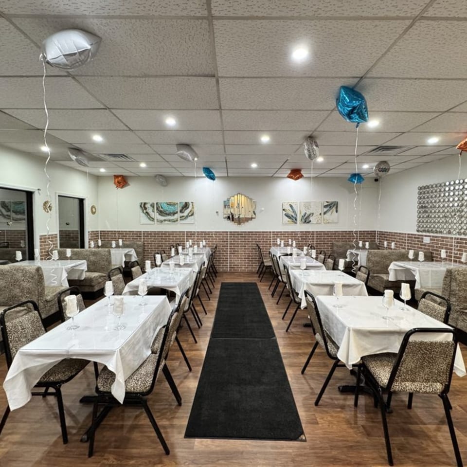 A decorated dining room at Café Butter Chicken with tables set for a party and balloons.