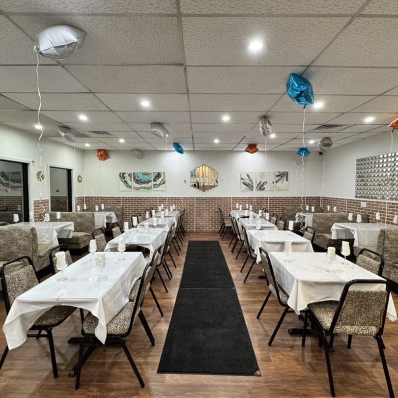 A decorated dining room at Café Butter Chicken with tables set for a party and balloons.