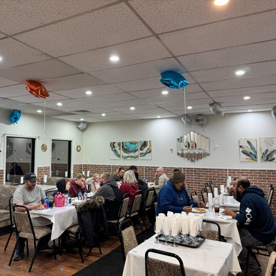 Diners enjoying Indian cuisine at tables in a brightly lit restaurant with brick accents and balloons.