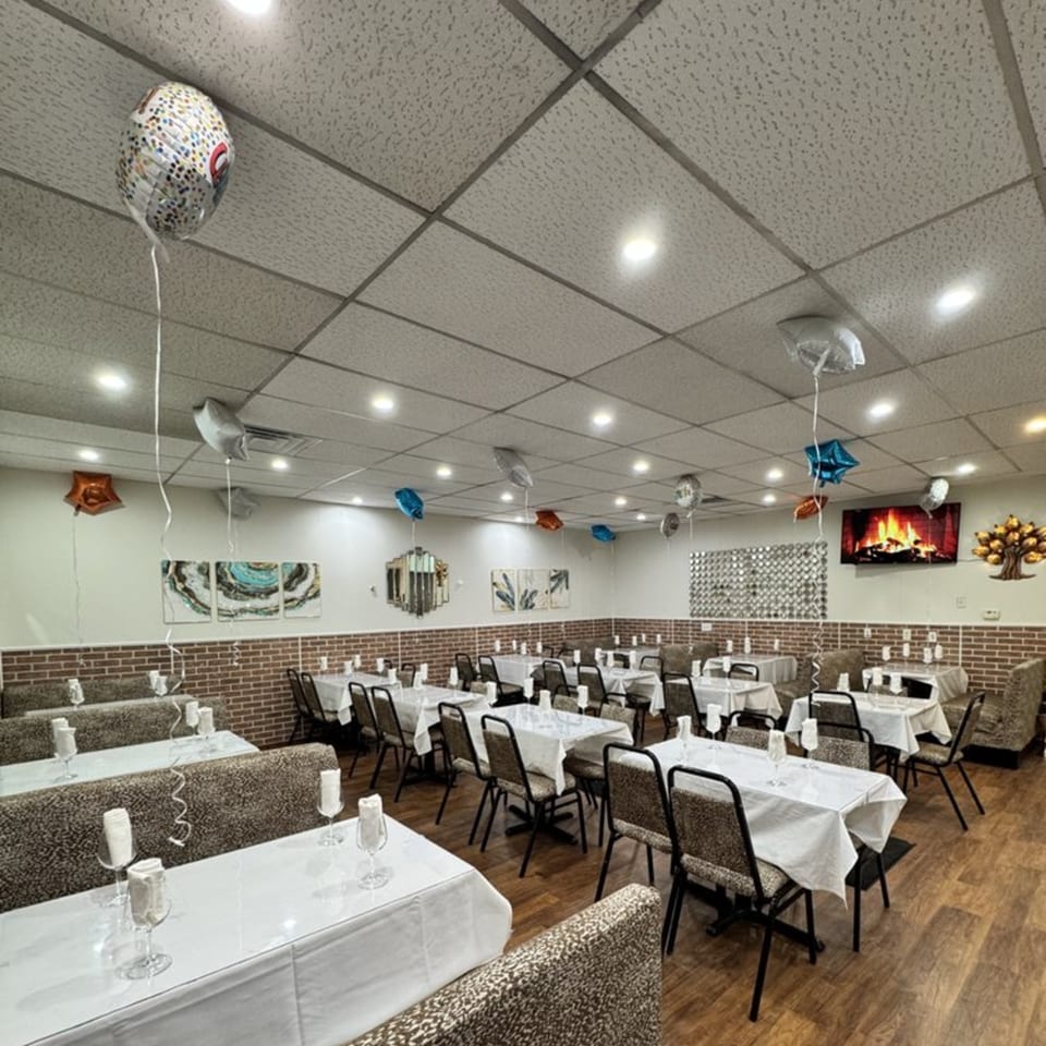 Spacious dining room at Café Butter Chicken with white-clothed tables, booth seating, and festive balloons.