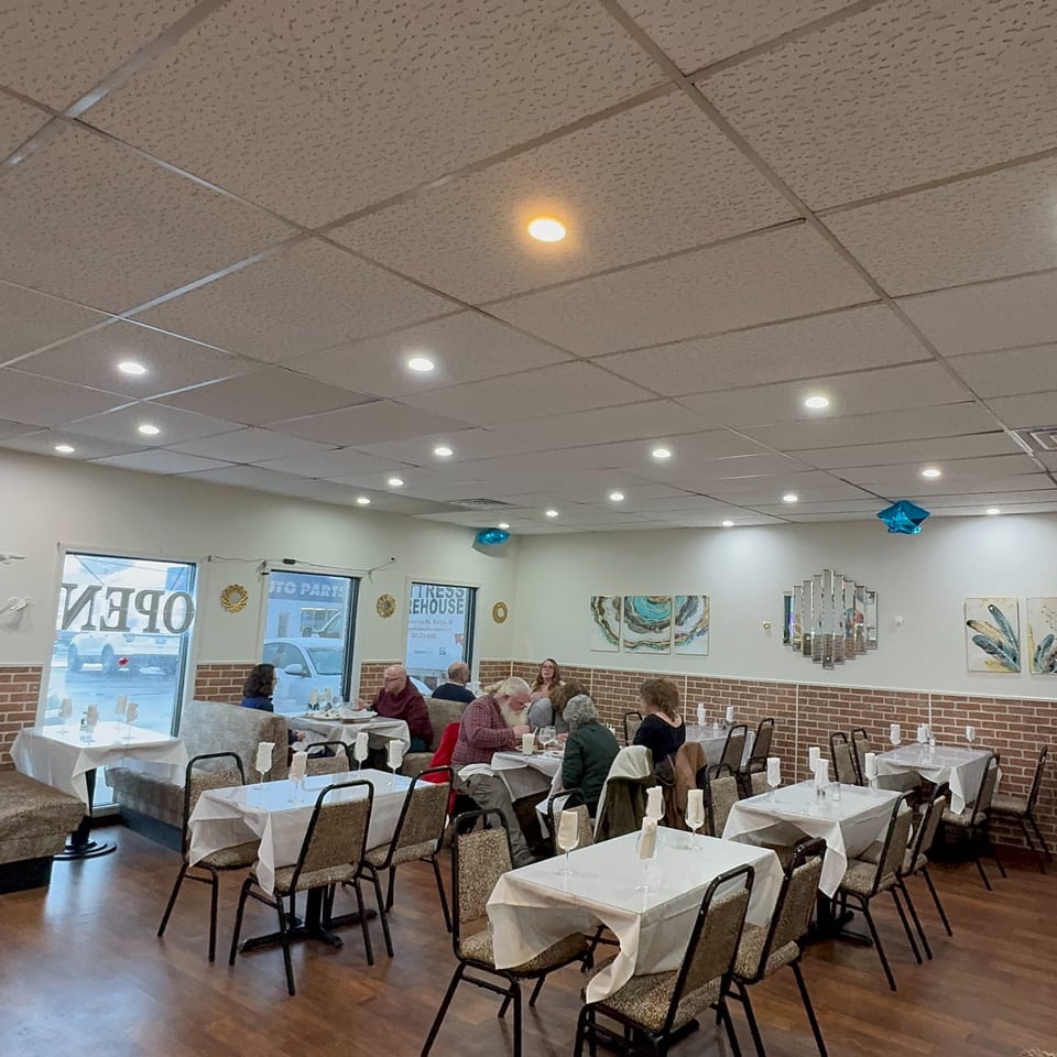 Diners seated at tables with white tablecloths in the brightly lit Café Butter Chicken dining room.
